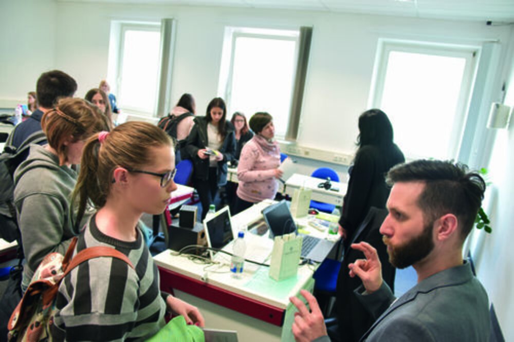 Besprechung im Klassenzimmer Gruppe von Personen im Raum bei einer Besprechung um einen Tisch mit Laptops und Unterlagen