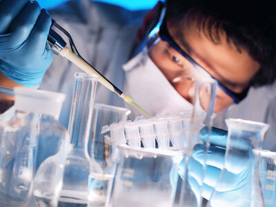 Wissenschaftler im Labor pipettiert Flüssigkeit in Reagenzgläser, umgeben von Laborgeräten
