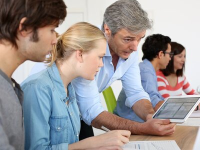 Gruppe bei einer Besprechung, eine Person hält ein Tablet