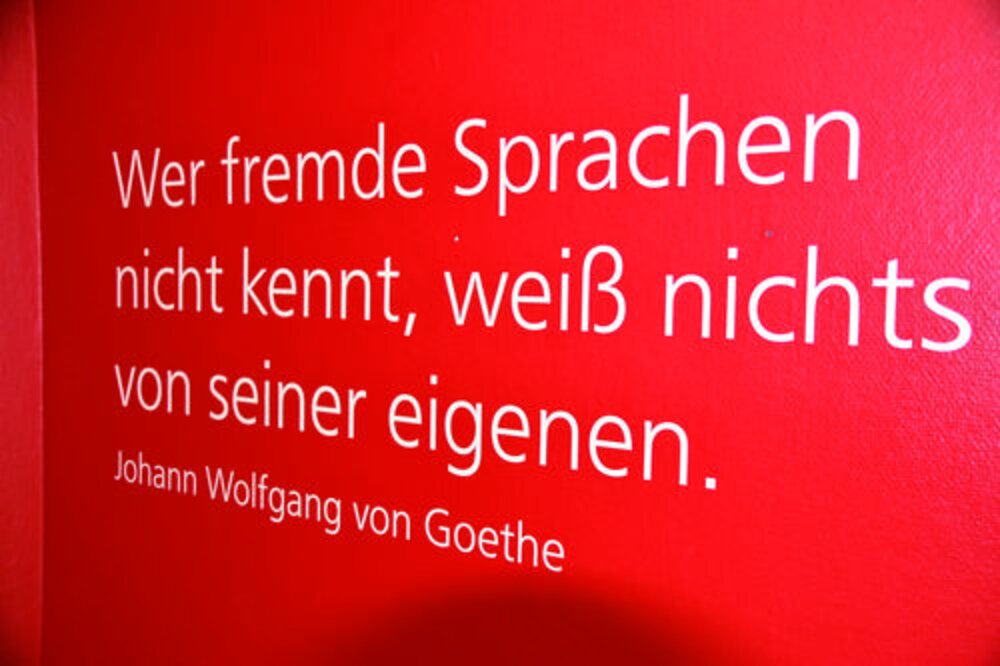 Goethes Zitat über die Bedeutung fremder Sprachen Ein Zitat von Johann Wolfgang von Goethe auf rotem Hintergrund. Das Zitat lautet: "Wer fremde Sprachen nicht kennt, weiß nichts von seiner eigenen."